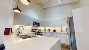 A modern kitchen with white cabinetry, stainless steel appliances, and a central island with a sink.
