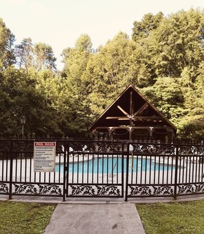 A pool area with a fenced deck, a wooden pavilion, and a sign detailing pool rules. - Blessed Nest 1 Bedroom Cabin by RedAwning (Townsend)