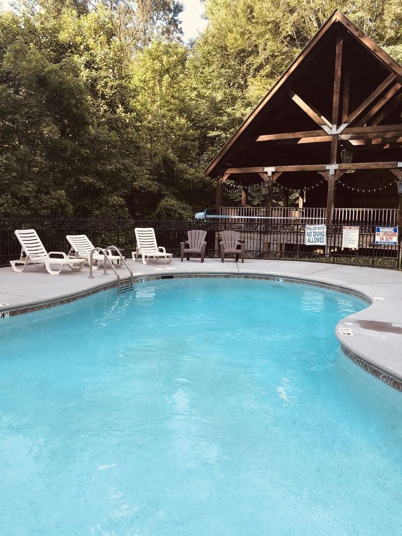 Ein Schwimmbecken mit Liegestühlen und einem Holzpavillon.