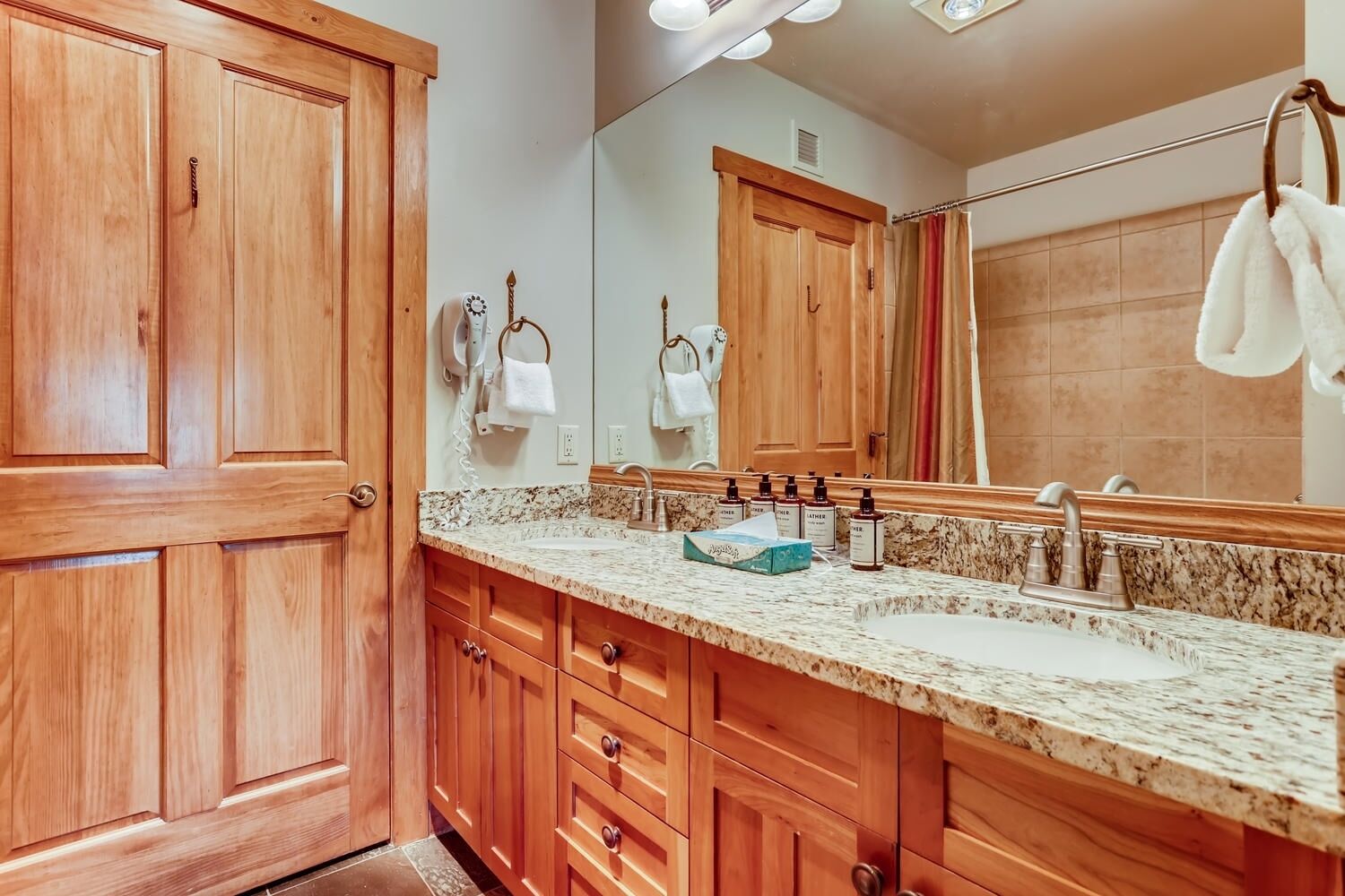 A wooden vanity with a granite countertop, a large mirror, and a towel rack.