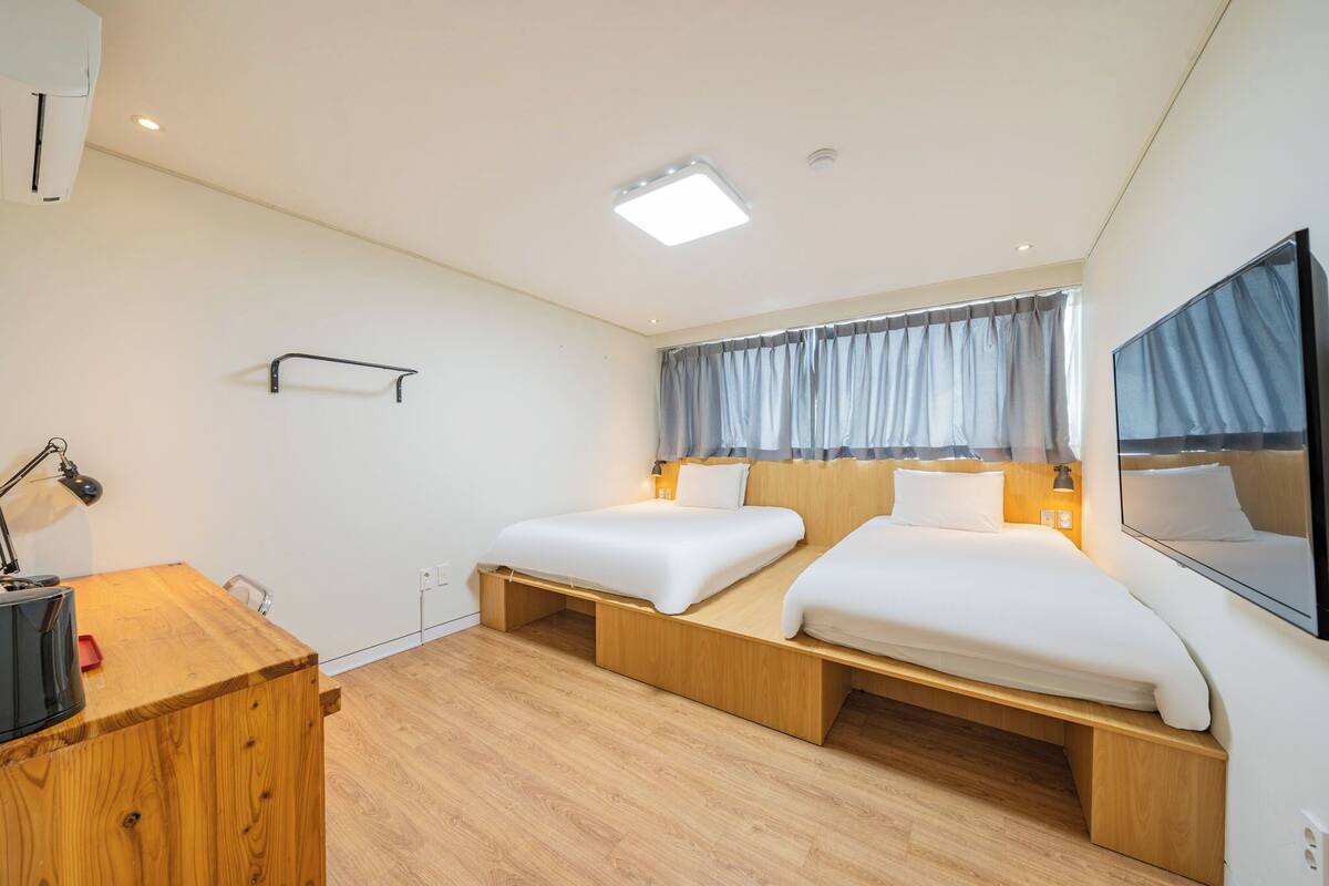 Una habitación de hotel moderna con dos camas, un escritorio y un espejo grande.