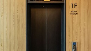 An elevator with a sign reading "1F RADIO STATION" and a control panel with accessibility symbols. - Dodubong Stay Hotel (Jeju City)