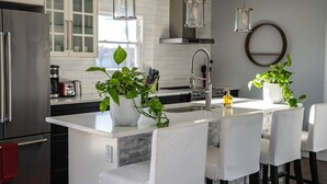 Een moderne keuken met een centraal eiland, roestvrijstalen apparatuur en hanglampen.