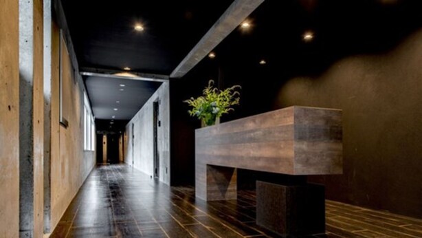 A hallway with a wooden floor, a reception desk, and a plant. - Stay's OTARU (Otaru)