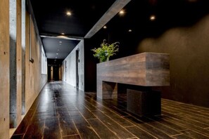 Un couloir avec un plancher en bois, un comptoir d’accueil et une plante.