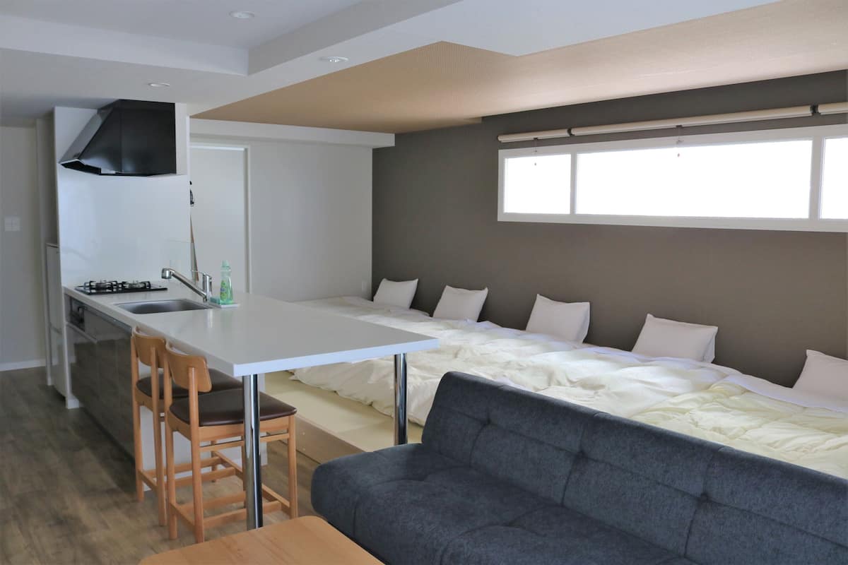 A compact living space with a kitchenette, a sofa, and a bed.