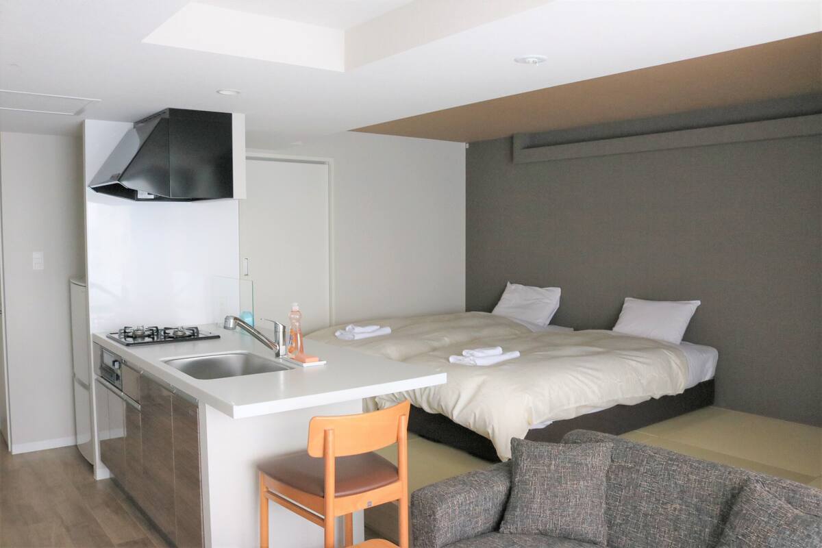 A compact room with a kitchenette, a bed, and a seating area.