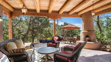 A covered patio area with wicker furniture, a round table, and a fire pit.