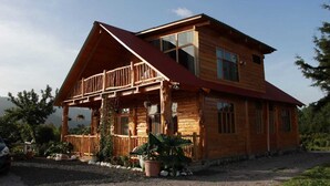 A wooden cabin with a balcony, large windows, and a gravel driveway. - Stunning Cabin w/360º view of Guatemala Highlands (Tecpán Guatemala)