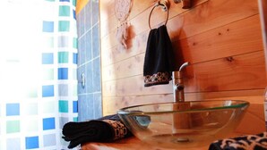 A bathroom with a glass bowl sink, a towel rack with a towel, and a dreamcatcher on the wall. - Stunning Cabin w/360º view of Guatemala Highlands (Tecpán Guatemala)
