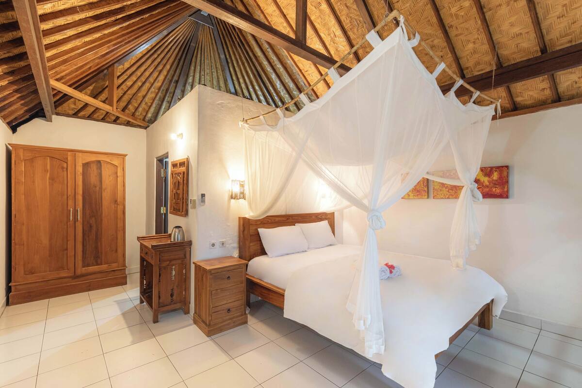 A bedroom with a wooden bed, a nightstand, a wardrobe, and a canopy bed.