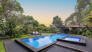 A rectangular pool with a tiled deck, surrounded by lush greenery and a gazebo. - Taman Indrakila (Ubud)