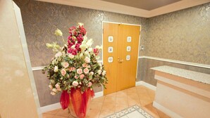 A reception area with a floral arrangement, a wooden door, and a tiled floor. - Hotel LaLa PAT1 - Adults Only (Sakai)