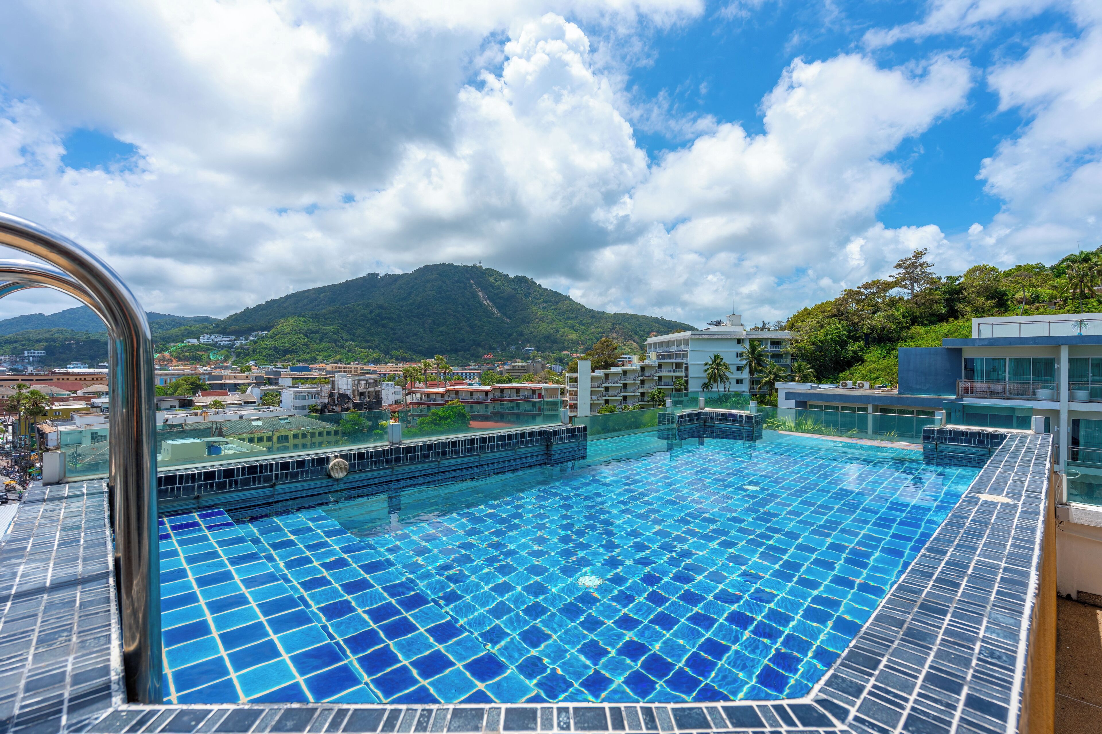 A rooftop infinity pool with a clear view of a mountain and cityscape.