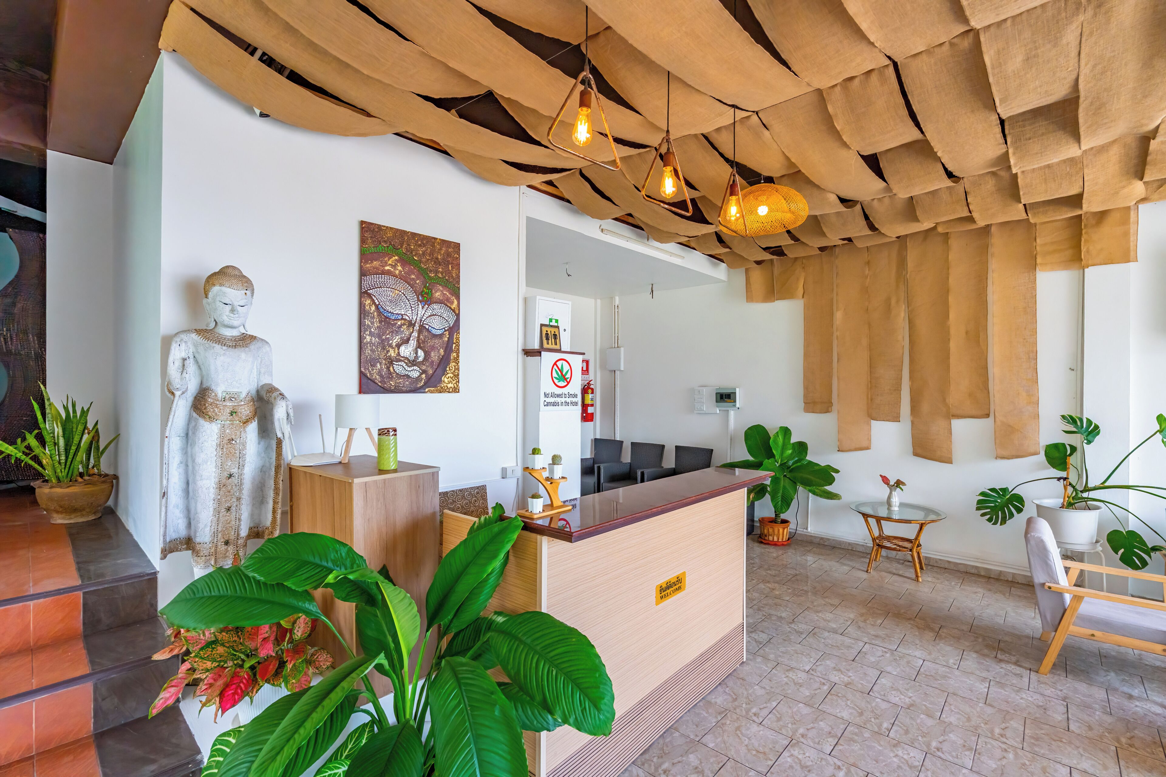 A reception area with a statue, a painting, a reception desk, and several potted plants.