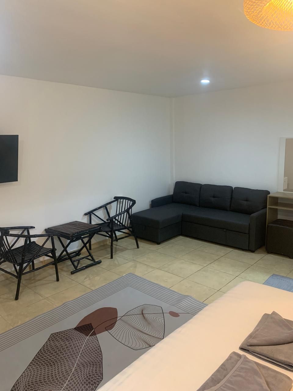 A modern living room with a sectional sofa, a small dining table with chairs, and a patterned rug.