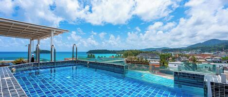 A swimming pool with a clear view of the ocean and mountains in the background.