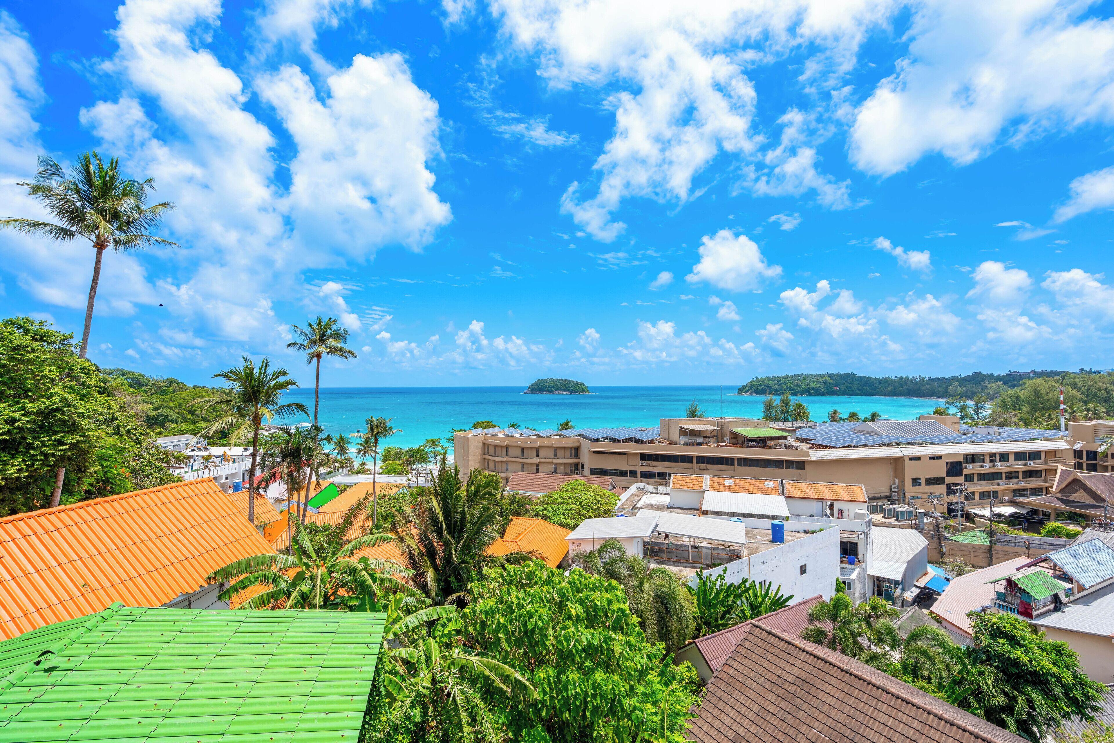 A coastal resort with multiple buildings, palm trees, and a view of the ocean.