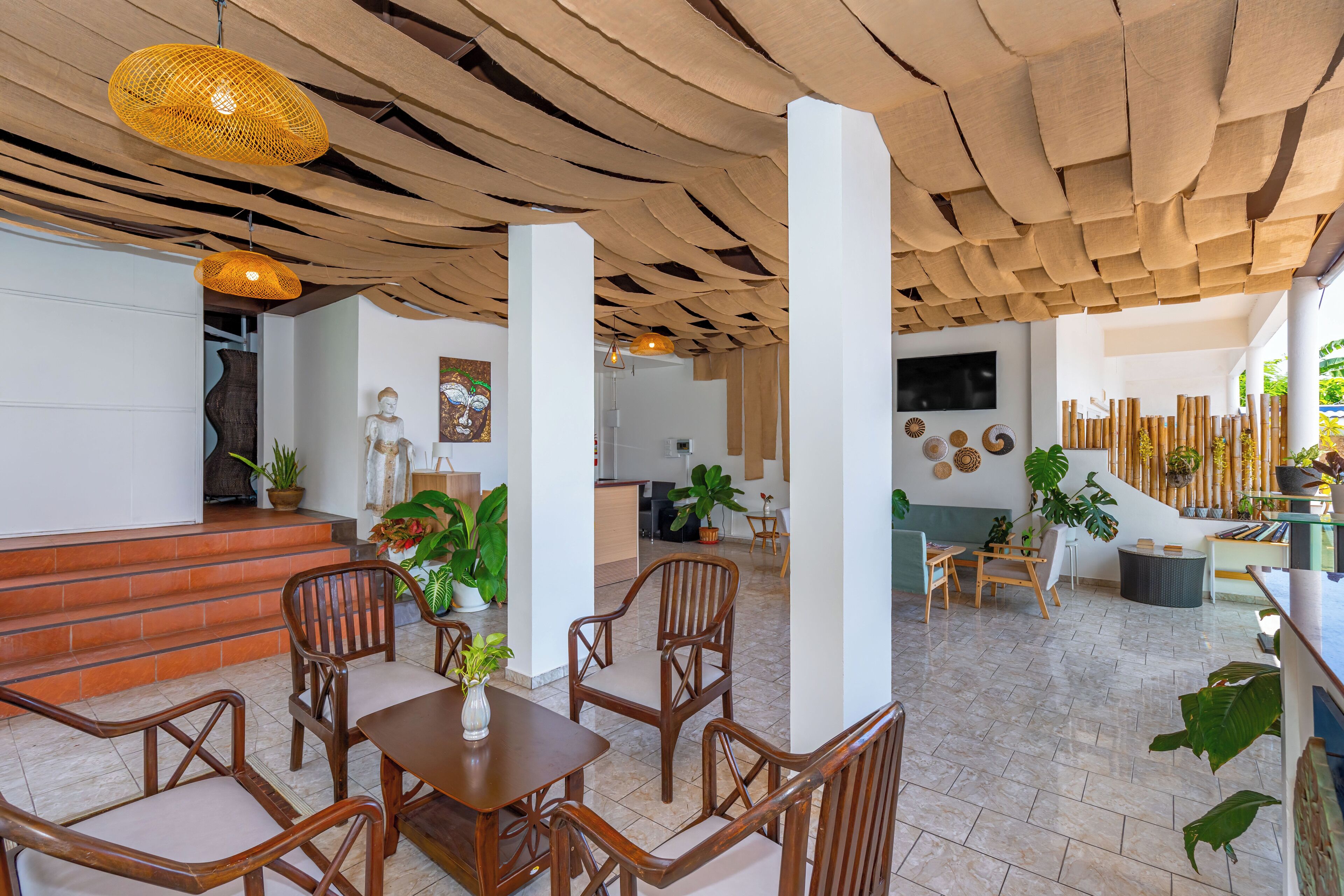 A spacious lobby with a wooden ceiling, a reception desk, and a seating area with wooden chairs and a table.