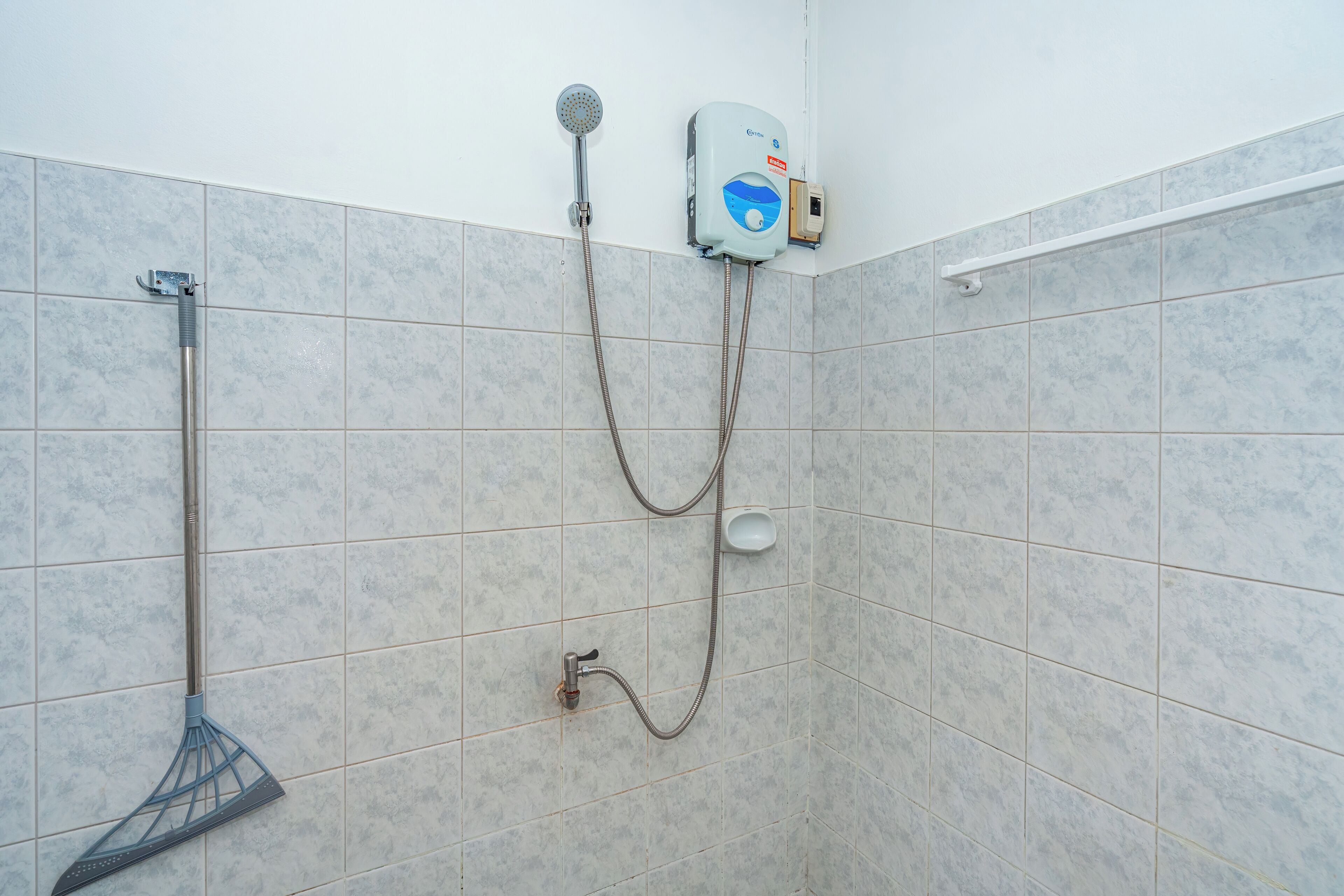 Una ducha con cabezal de ducha de mano, panel de control en la pared y cepillo de ducha manual.