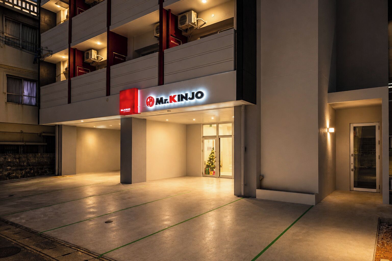 A hotel entrance with a sign for 'Mr. KINJO' and a Christmas tree inside.