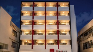 A multi-story hotel with a central red vertical feature, multiple balconies, and air conditioning units.