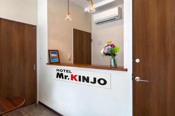 A hotel reception desk with a sign reading "HOTEL Mr. KINJO".