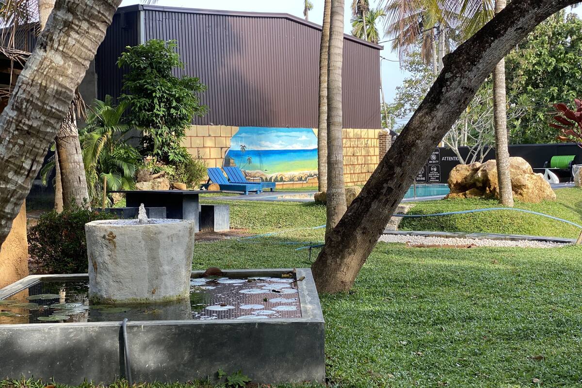 Un espace aménagé avec un élément aquatique, des sièges et une fresque sur un bâtiment.