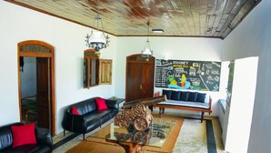 A living room with a glass coffee table, black leather sofas, wooden doors, and a chalkboard wall with text. - Rohoney Boutique Villa (Galle)