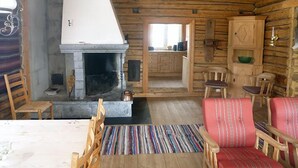 A rustic cabin interior with a stone fireplace, wooden furniture, and a cozy seating area. - Skeikampen Appartement (Gausdal)