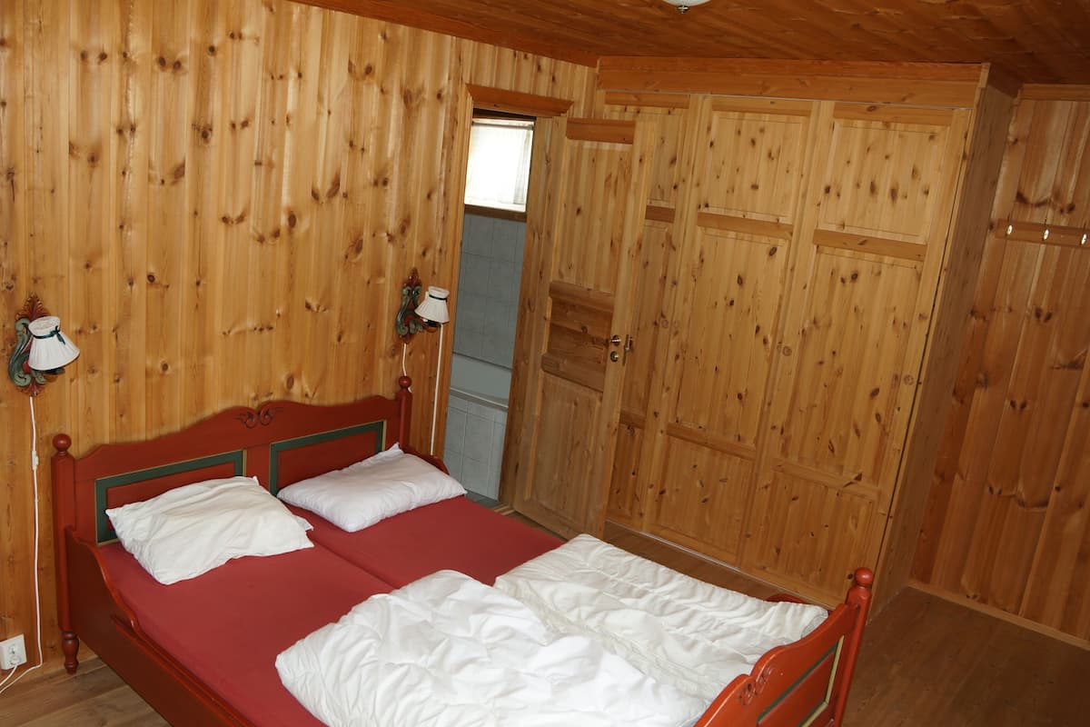 Una habitación de madera con una cama, una ventana y una puerta.