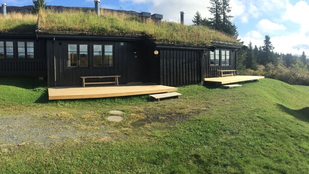 Two cabins with grass roofs, wooden decks, and a natural hillside backdrop. - Skeikampen Appartement (Gausdal)