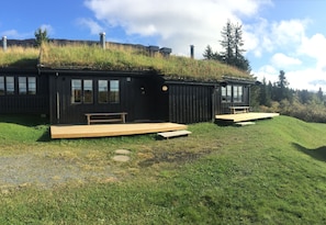 Two cabins with grass roofs, wooden decks, and a natural hillside backdrop. - Skeikampen Appartement (Gausdal)