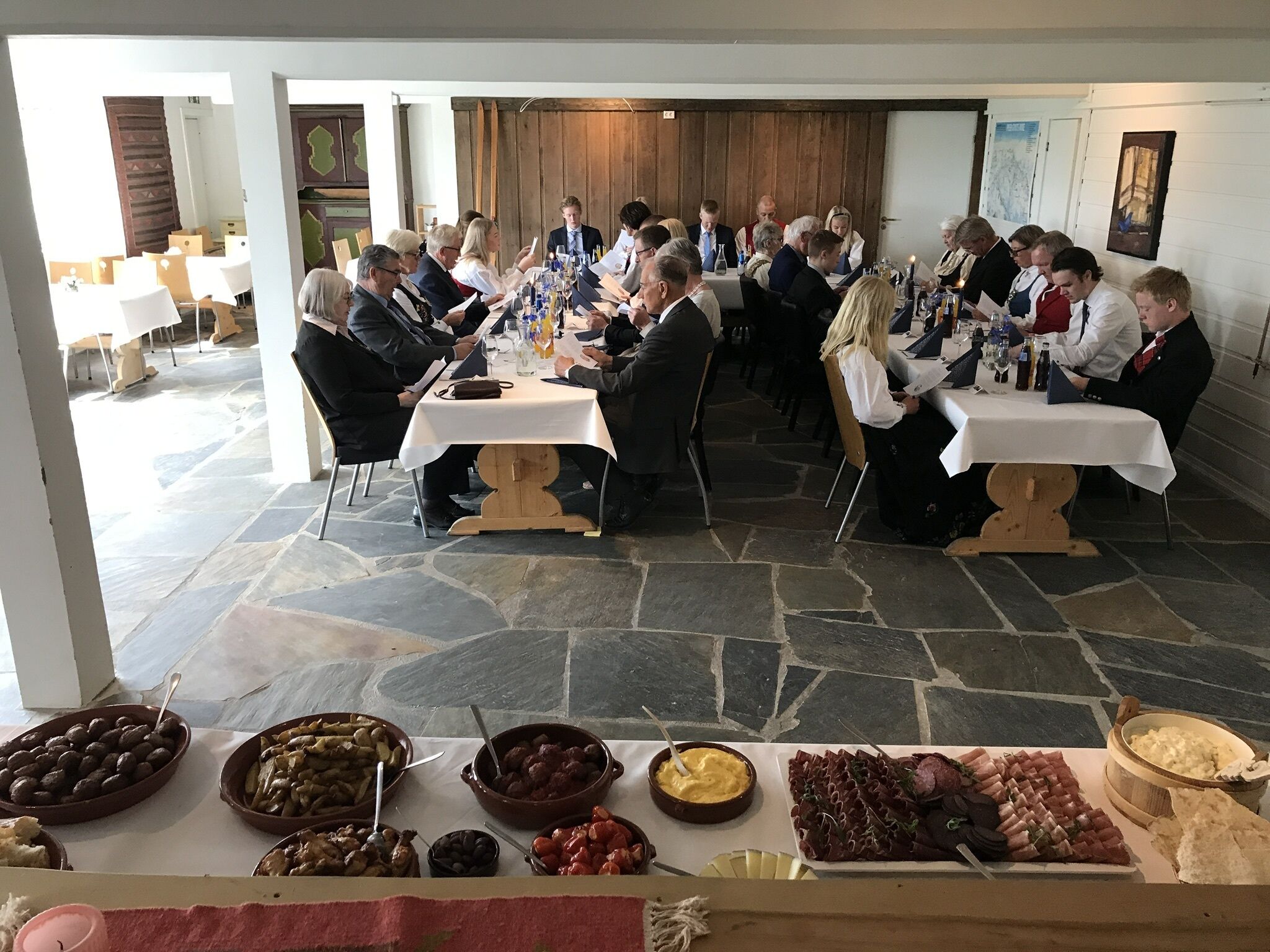 En elegant spisesal med stengulv, flere borde og et udvalg af madfade.