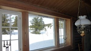 A cabin with large windows, wooden walls, and a hanging light fixture. - Skeikampen Appartement (Gausdal)