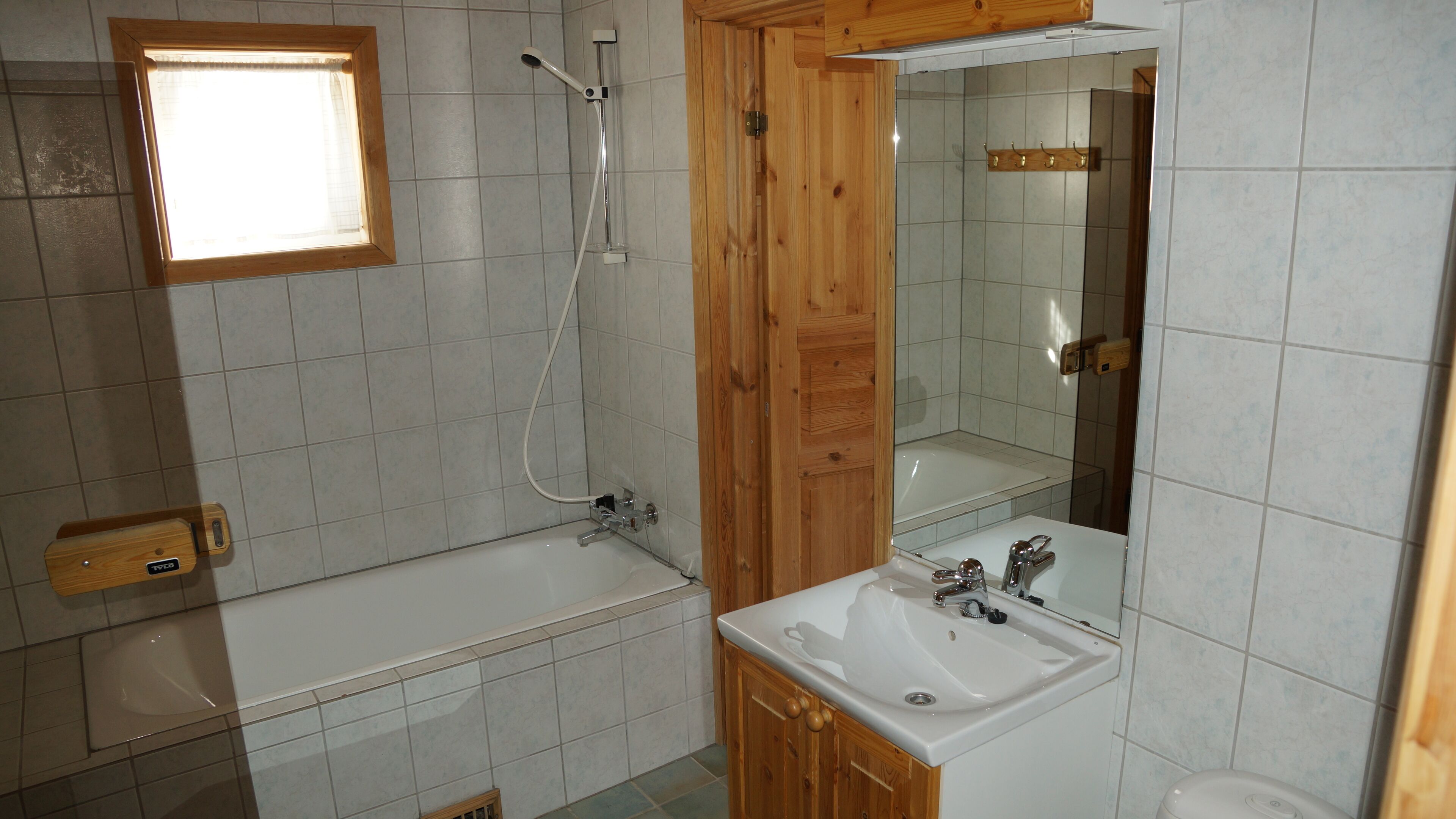 Ein Badezimmer mit einem Holzkosmetikschrank, einer Badewanne und einer Dusche.