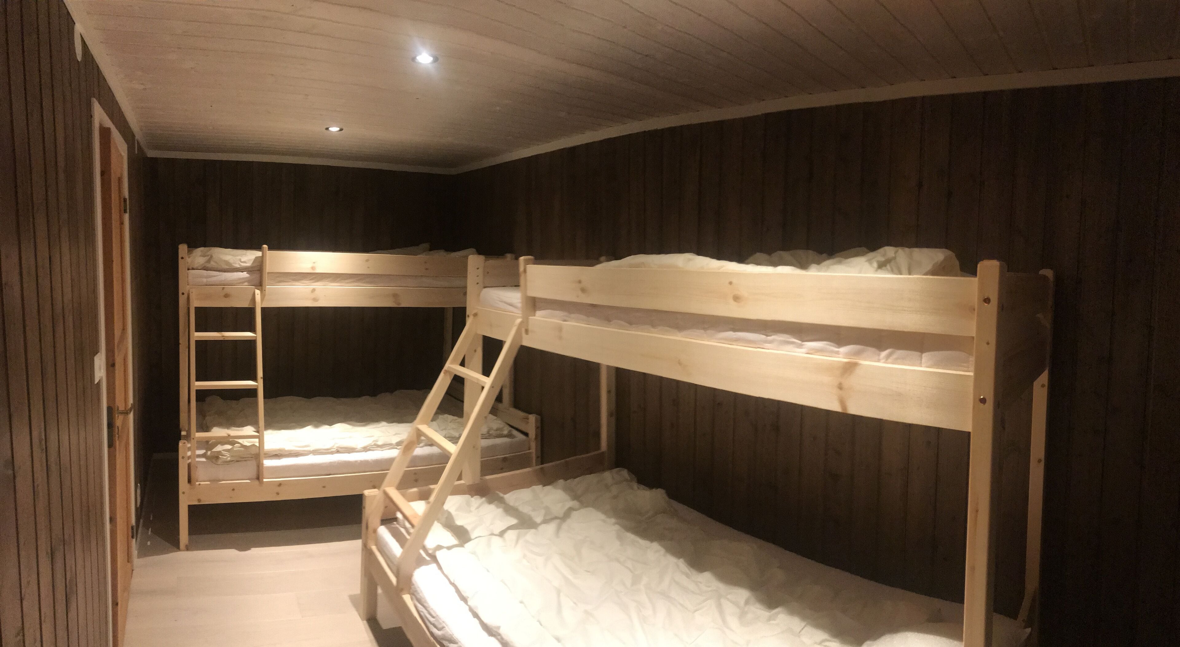 A bunk bed room with wooden walls and a sloped ceiling.