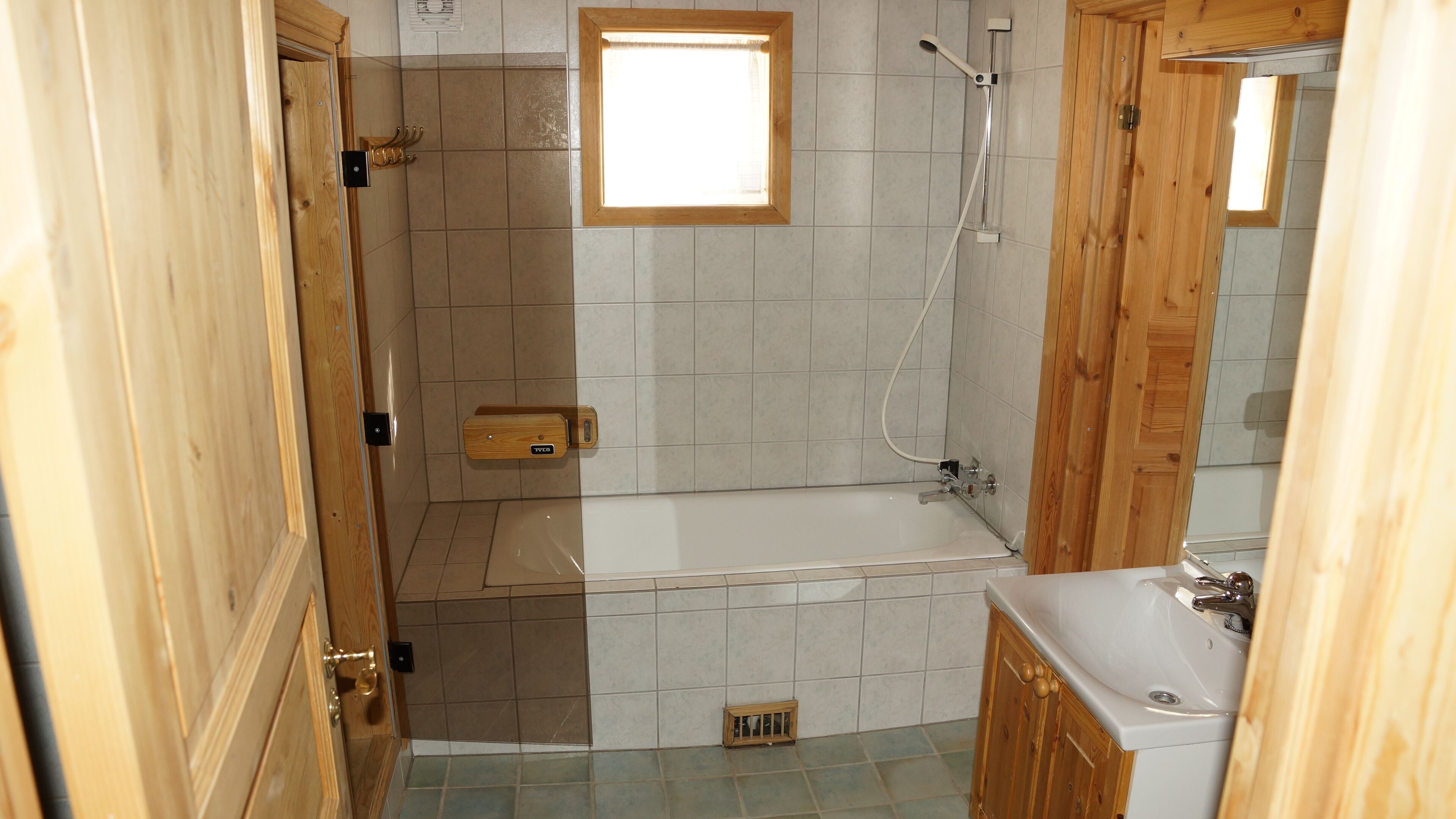 Un baño con bañera, ducha, inodoro y un armario de madera.