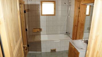 Un baño con bañera, ducha, inodoro y un armario de madera.