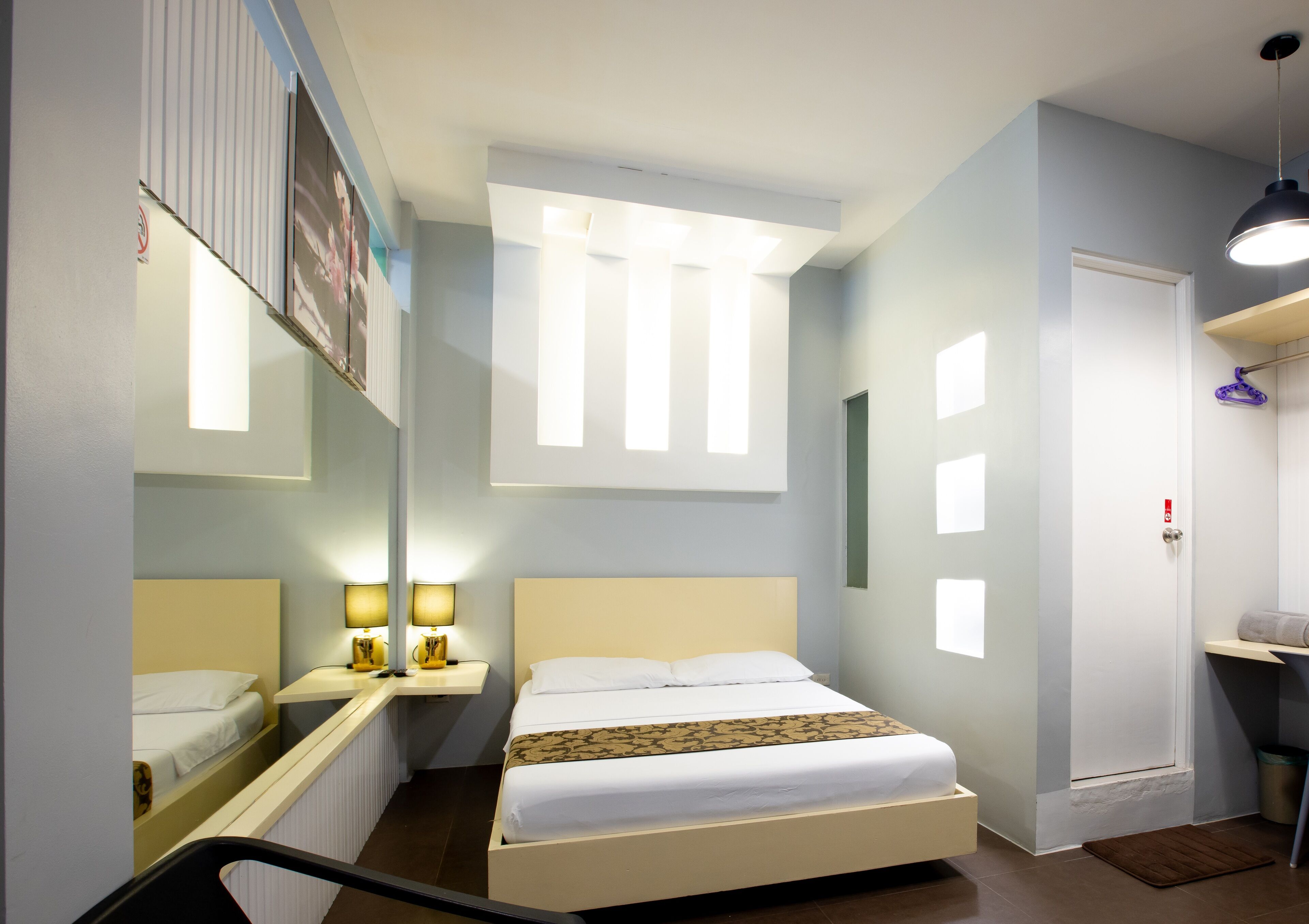 Ein Hotelzimmer mit einem Bett, Nachttischen, einem Spiegel, einem Fenster und einer Tür.
