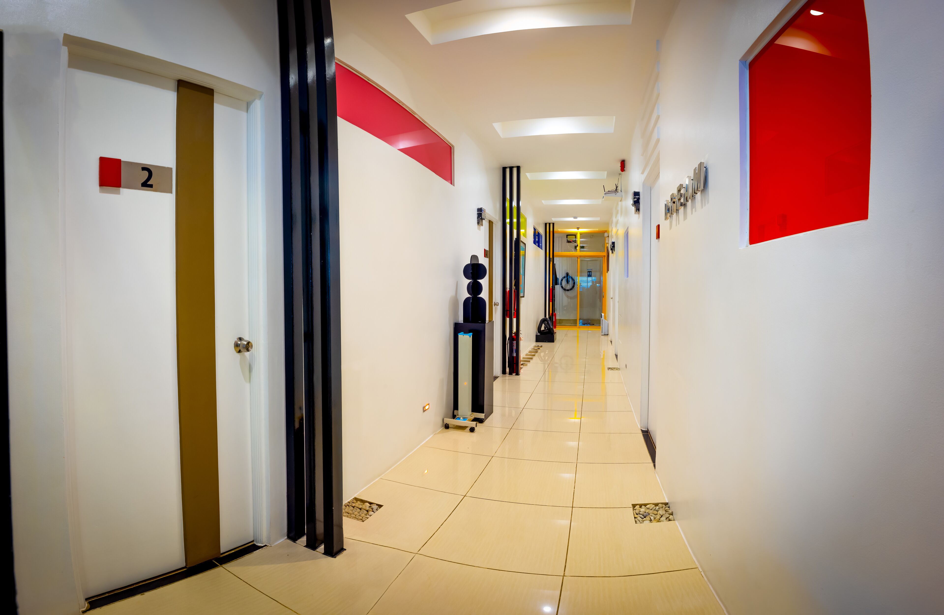 A hotel hallway with a clean, modern design, featuring a number sign on the wall, a mirror, and a luggage cart.
