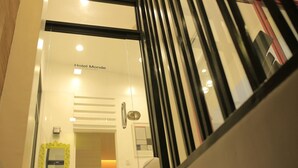 En hotelindgang med en glasdør, en receptionsdisk og et skilt med teksten "Hotel Monde".
