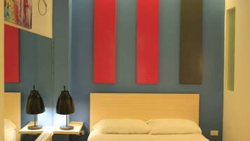 A hotel room with a bed, bedside tables, and a wall-mounted air conditioner.