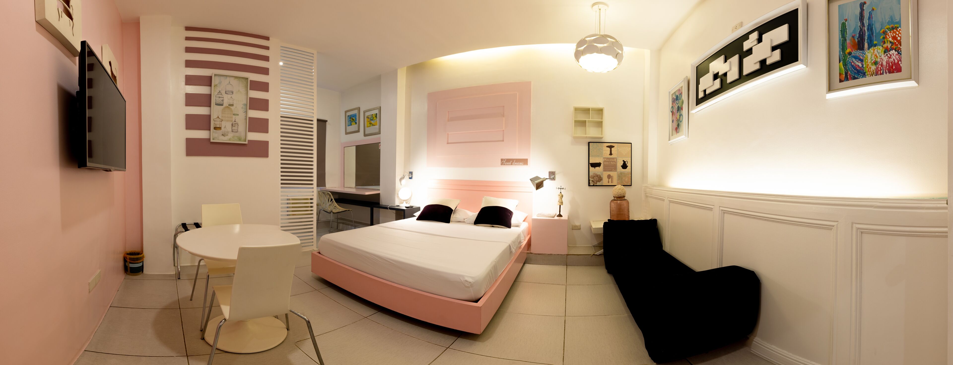 A modern bedroom with a bed, bedside table, chair, and a TV mounted on the wall.