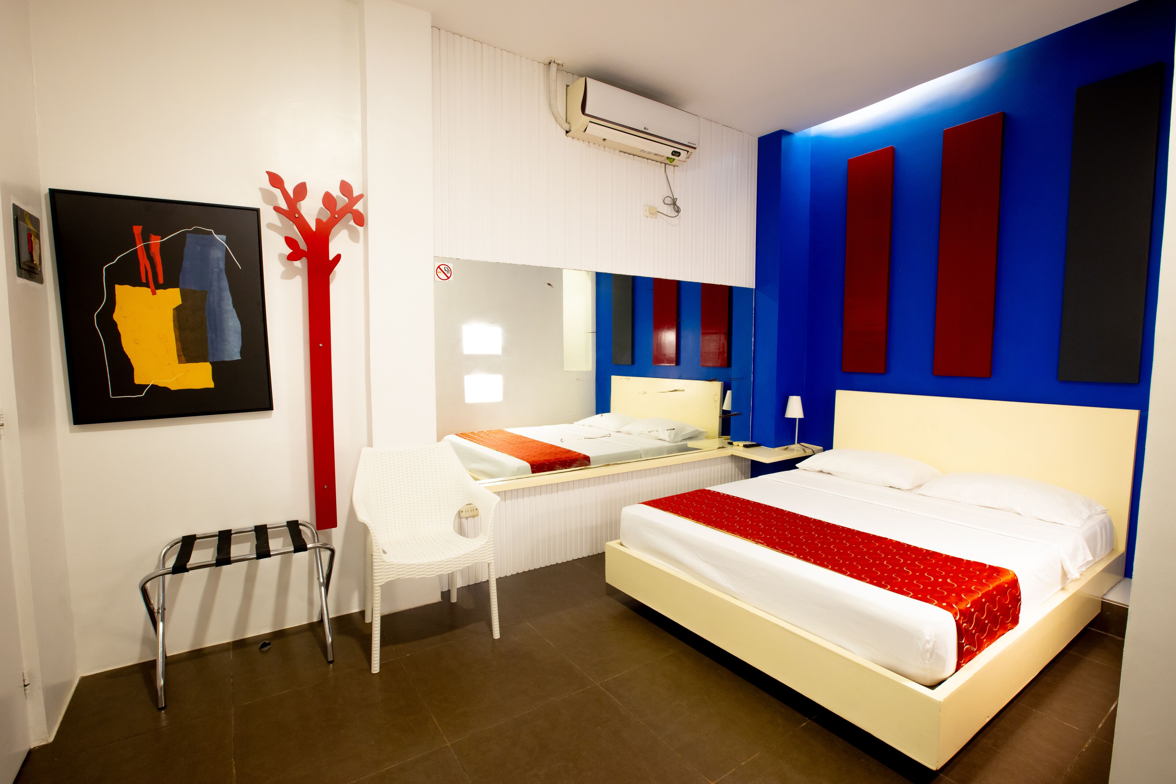 Una camera d'albergo moderna con un letto grande, una scrivania, una sedia e un condizionatore d'aria a parete.