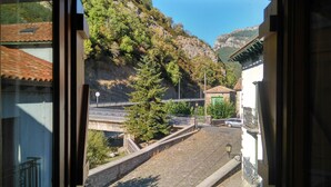 A view through a window of a street with a bridge, a river, and a mountain backdrop. - Lezegorria (Urzainqui)