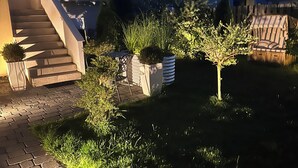 Un espace extérieur résidentiel aménagé avec un chemin pavé, un escalier et diverses plantes et arbustes.