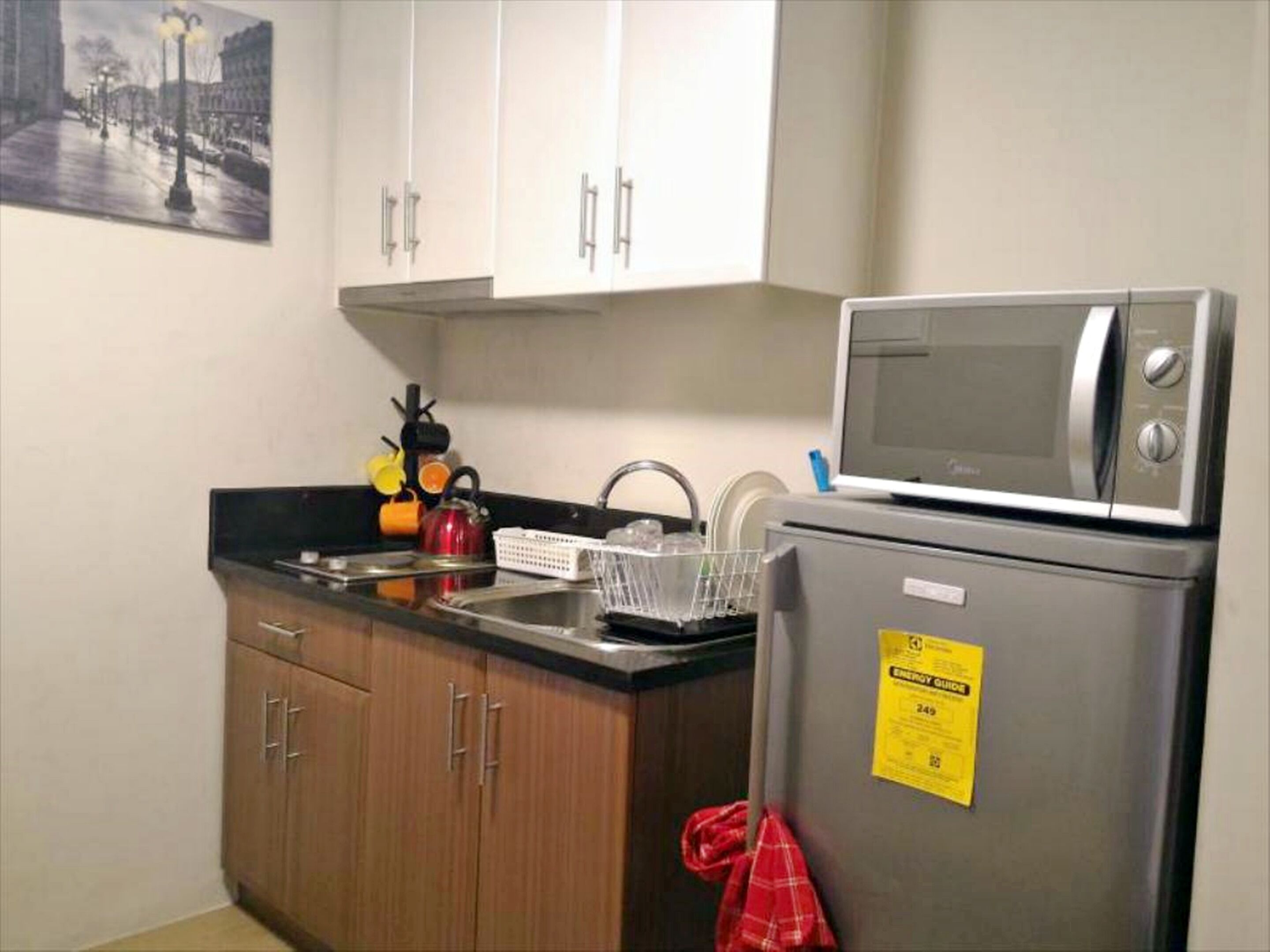 A compact kitchen with a microwave, a refrigerator, and wooden cabinets.