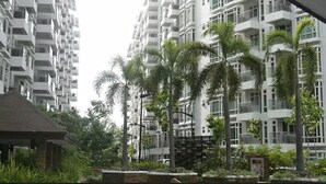 Un edificio residencial de gran altura con múltiples balcones, rodeado de palmeras y vegetación.
