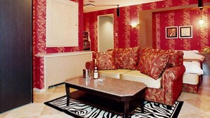 Una sala de estar con un sofá rojo estampado, una mesita de centro, un tapete con estampado de cebra y un espejo grande en la pared.